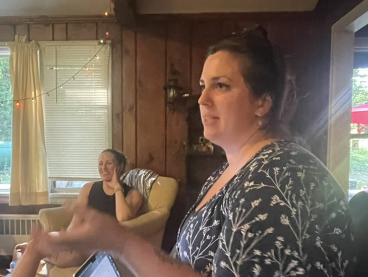 Colleen in the background and Cait near the camera, both focused on workshop talk