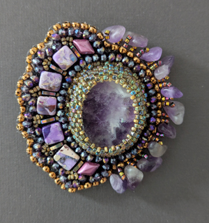 The brooch that Rachel Baker began fashioning during SwampFire. The center stone and the "fringe" stones are amethyst, with jasper accents. Rachel designed it so it can also be worn as a necklace pendant. 